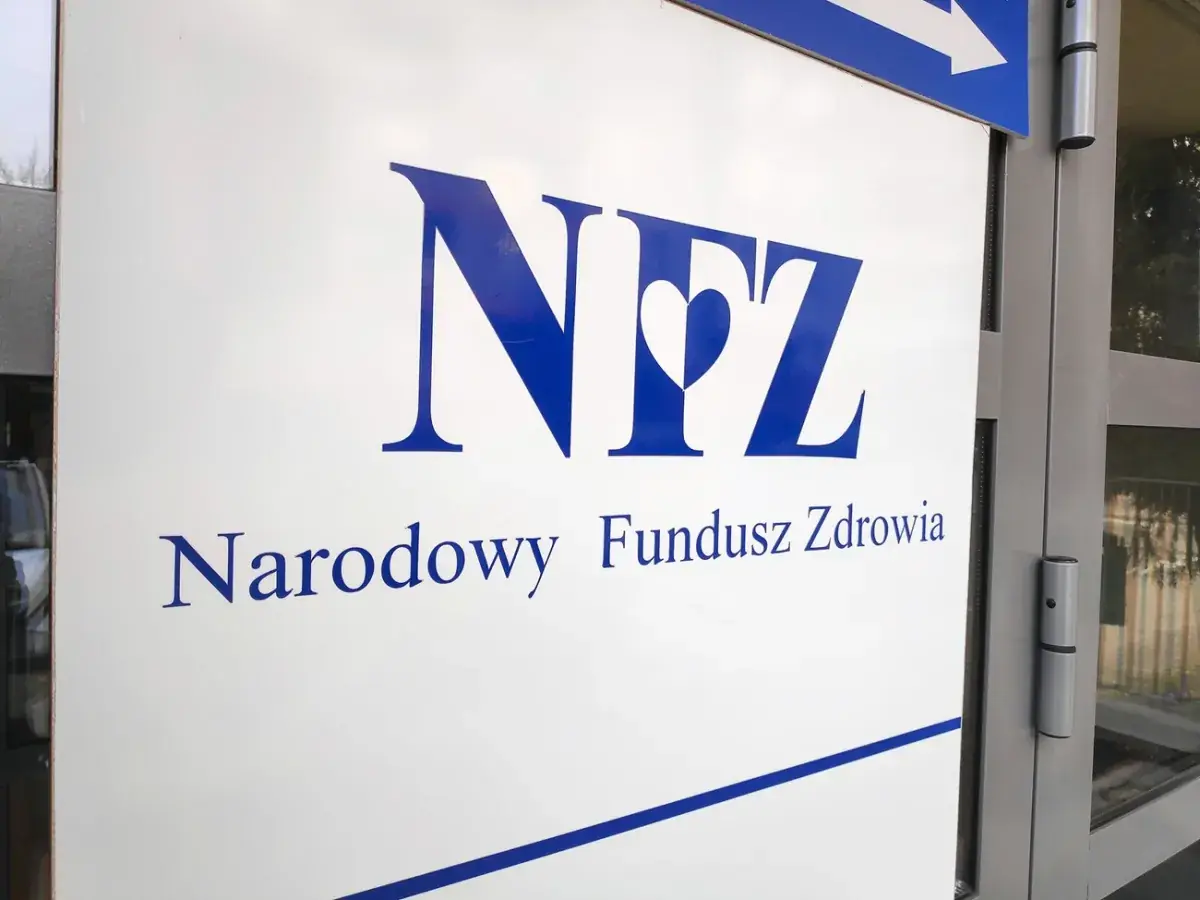 Tablica z logo Narodowego Funduszu Zdrowia przy wejściu do budynku